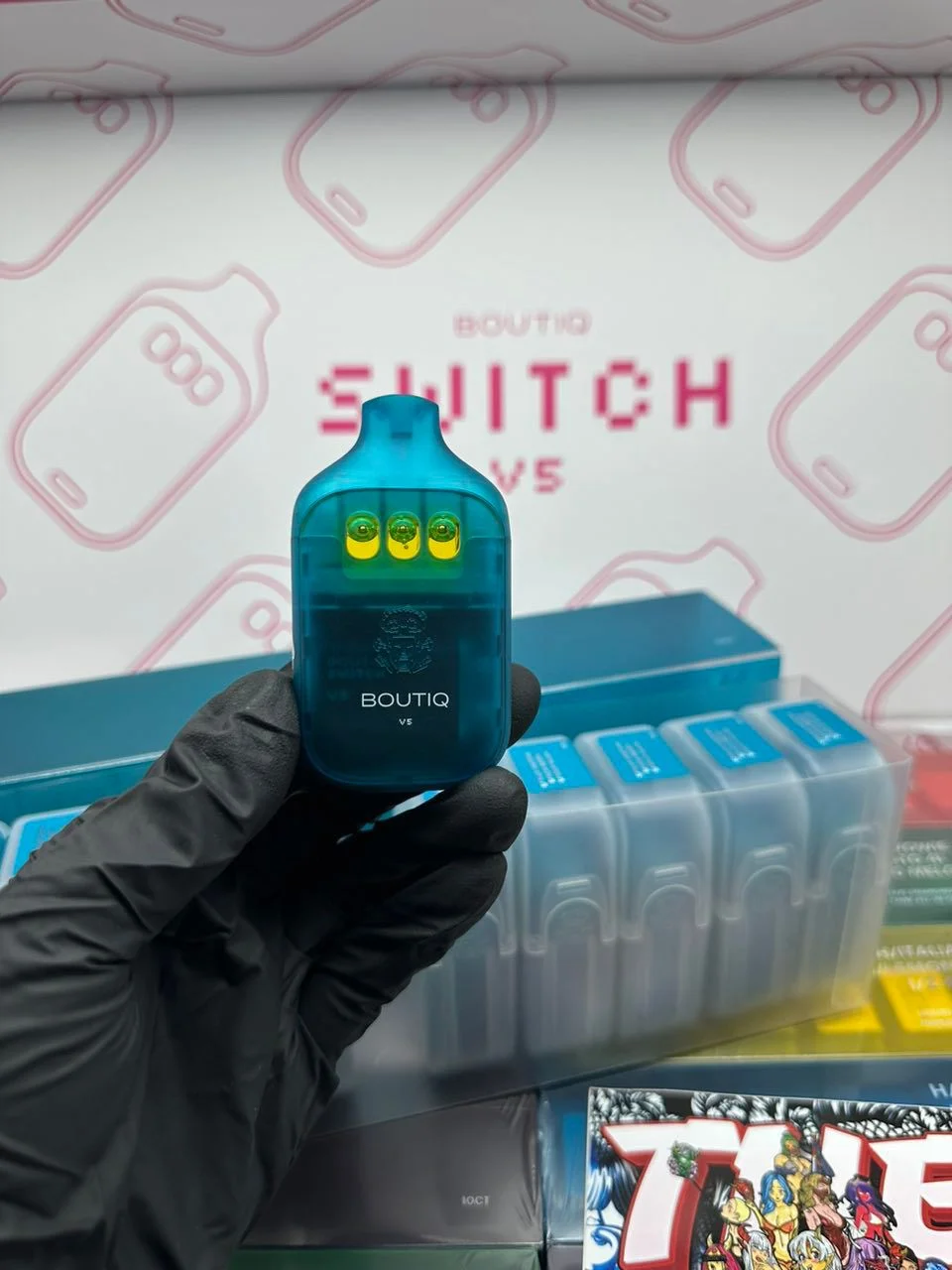 Blue Boutiq V5-labeled device held in a gloved hand in front of Switch V5 packaging.