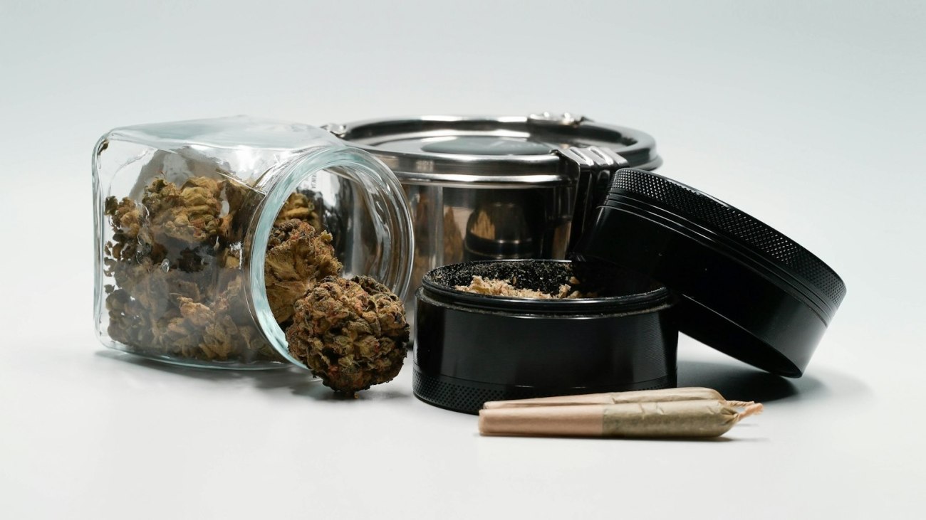 Cannabis flower in a glass jar beside an open lid